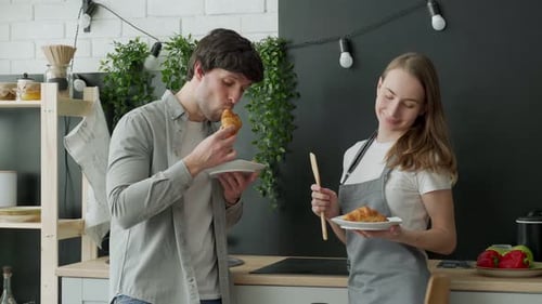 Couple Enjoying Croissants in a Bright Kitchen