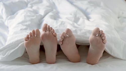 Passionate Loving Couple Having Sex Under White Blanket in Bedroom Close Up of Male and Female Feet
