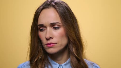 Sad Woman Looking Down on Yellow Background