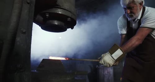 Senior Blacksmith Forging Hot Metal Rod with Press