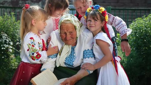An Old Grandmother is Sitting on the Street and Reading a Book