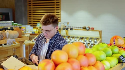 Young Man is Shopping in Grocery Choosing Citrus Fruits