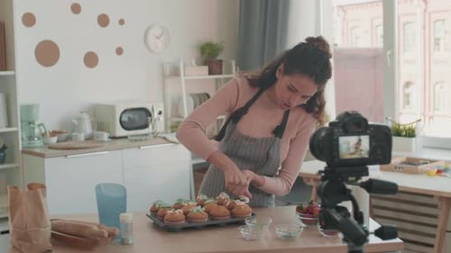 Woman Decorating Cupcakes for Camera in Kitchen
