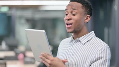 Young Man Video Calling on Tablet in Office