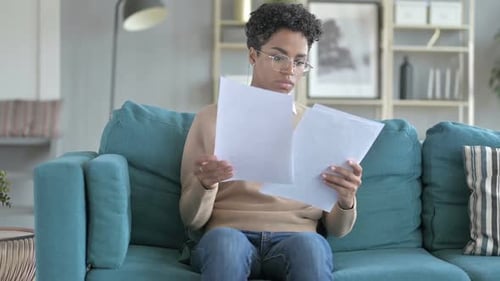 Young Woman Reading Documents on Couch At Home