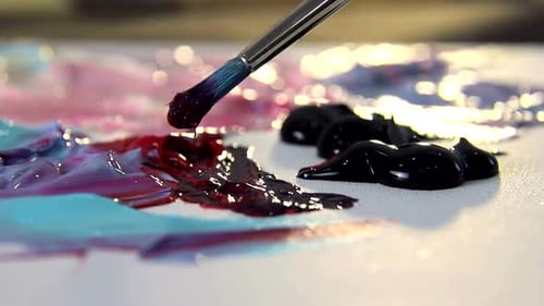 L'artiste mélange différentes couleurs de peinture acrylique avec un pinceau pour dessiner. Préparation des couleurs pour