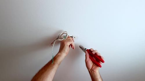 Close Up Cutting Ceiling Wires With Pliers