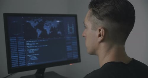 Back View of Man Programmer Working on Computer at Data Center