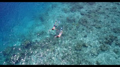 Two people tanning on paradise seashore beach voyage by transparent sea with white sand background o