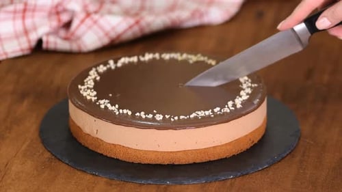 Pastel de mousse de chocolate cortado a mano con las manos del pastelero.