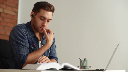 Closeup of Thoughtful Young Man Searching Information Flipping Pages of Book Searching for Reference