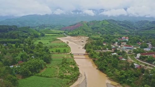 Drone Flies Along River Running Among Tropical Landscape