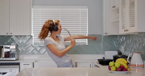 Woman with Headphones Dances in Kitchen