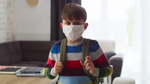 Child Wearing a Mask and Backpack Indoors