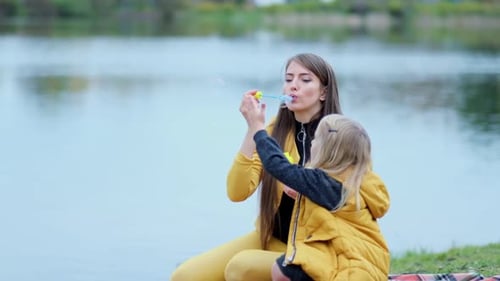 Woman and Child Blowing Bubbles by Lake