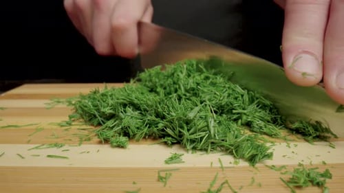 Male Hands with a Knife Cutting Green Dill Sprigs