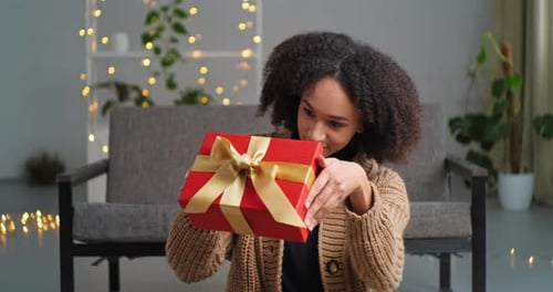 Woman Holding Gift in Cozy Home Setting