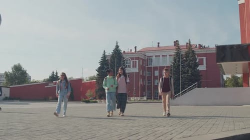 Students Walking Away From School Building on Sunny Day