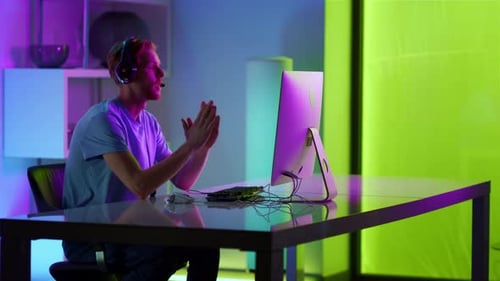 Trauriger Kerl verliert Computerspiel im Neonzimmer