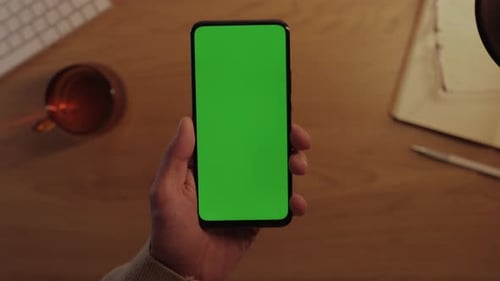 Male Hands Holding Smartphone with Green Mockup Screen