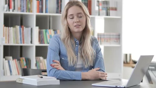 Woman Sits at Desk with Laptop and Books