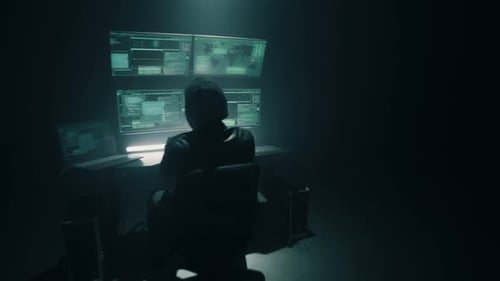 Male Cyber Criminal Using Computer Under Spotlight