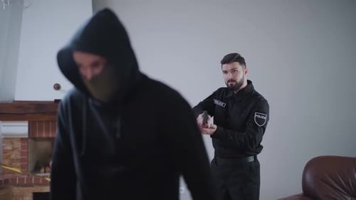 Police Officer Confronting Hooded Suspect with Gun Drawn