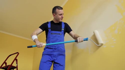 Young man renovating new house and painting interior walls