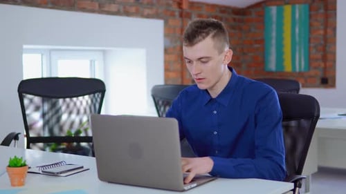 Young Man Working on Laptop in Loft Styled Office