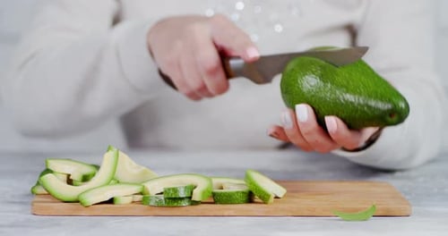 Cutting fresh green avocado on wooden board