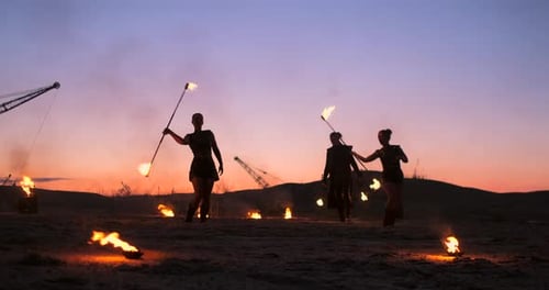Professionelle Künstler zeigen eine Feuershow bei einem Sommerfestival im Sand in Zeitlupe