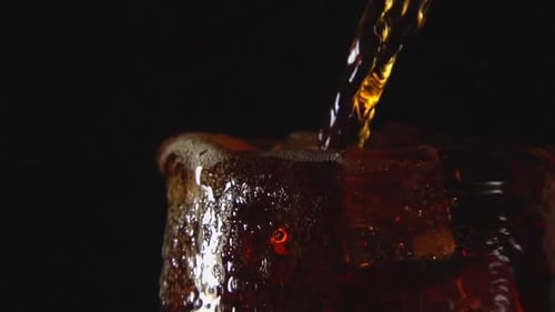 Dark Beverage Being Poured into Glass with Ice
