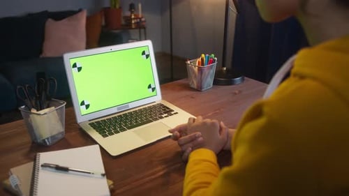 Beautiful Black Woman Sitting at Her Desk Works on a Laptop with Green Chroma Key Mockup Screen