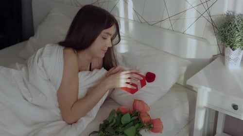 Woman Opens a Gift While Lying in Bed