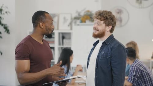Men Discuss Business Documents in Bright Office