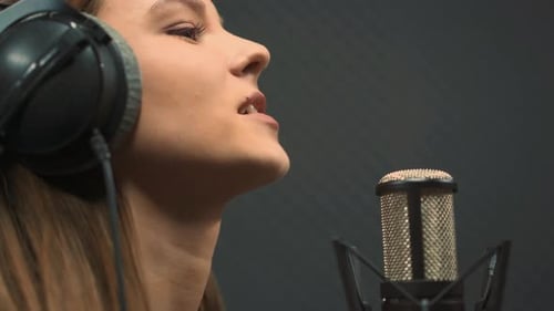 Singer with Headphones Singing Into Microphone in Studio