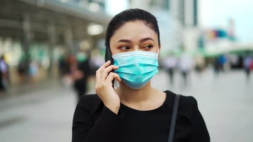 business woman talking with smartphone and wearing medical mask for protection from coronavirus