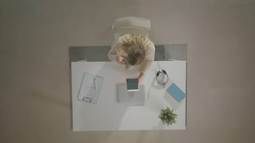 Overhead View of Woman Using Tablet at Desk