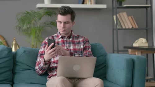 Young Adult Working with Laptop and Mobile Phone at Home