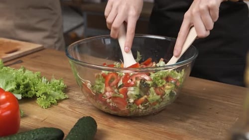 Salat zu Hause kochen Frauenhände mischen frischen Gemüsesalat auf Holztisch in moderner Küche