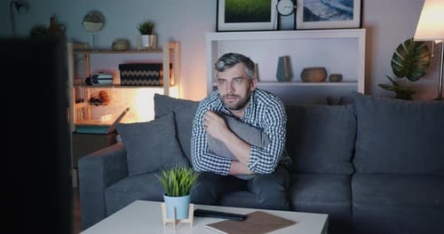 Middle-aged Bachelor Watching Scary Film on TV at Night Sitting on Couch Alone