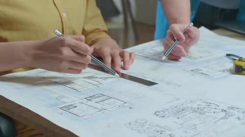 Close Up Of Hand's Woman And Man Engineers With Blueprint Discuss About Design At The Office