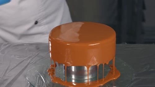 Brown Glaze Being Poured on Cake in Kitchen