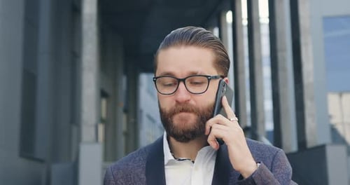 Businessman in Glasses Talking on Phone and Drinking Coffee Near Office Building During Time Break