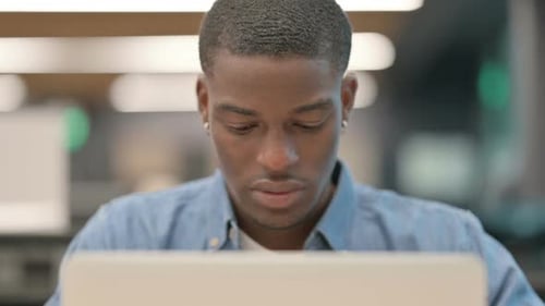 Young Adult Rubbing Temples at Laptop