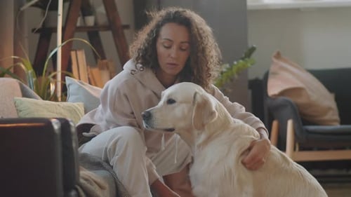 Woman Cuddles with Golden Retriever Dog at Home