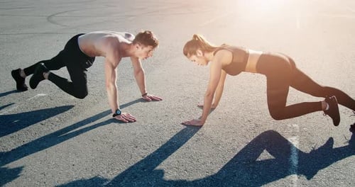 Athletic Couple Doing Mountain Climber Exercises Outdoors