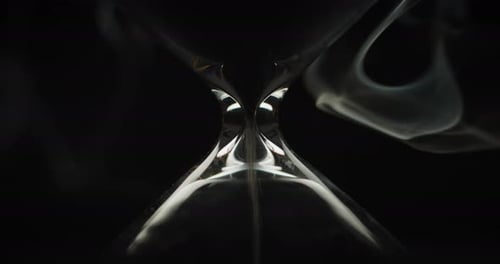Sand pouring in hourglass with smoke