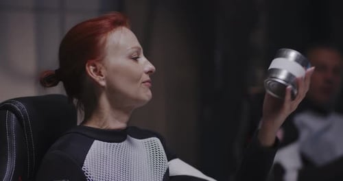 Woman Holds Can Wearing Spacesuit in Futuristic Setting