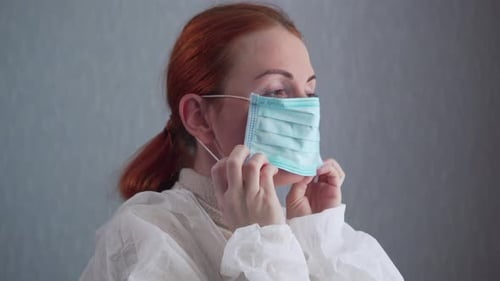 Woman Putting on Protective Mask and Coveralls